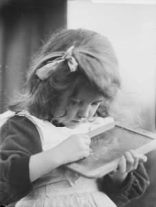 Photo of a young girl using a slate taken by Harold Cazneaux about a century earlier than the invention of the ipad